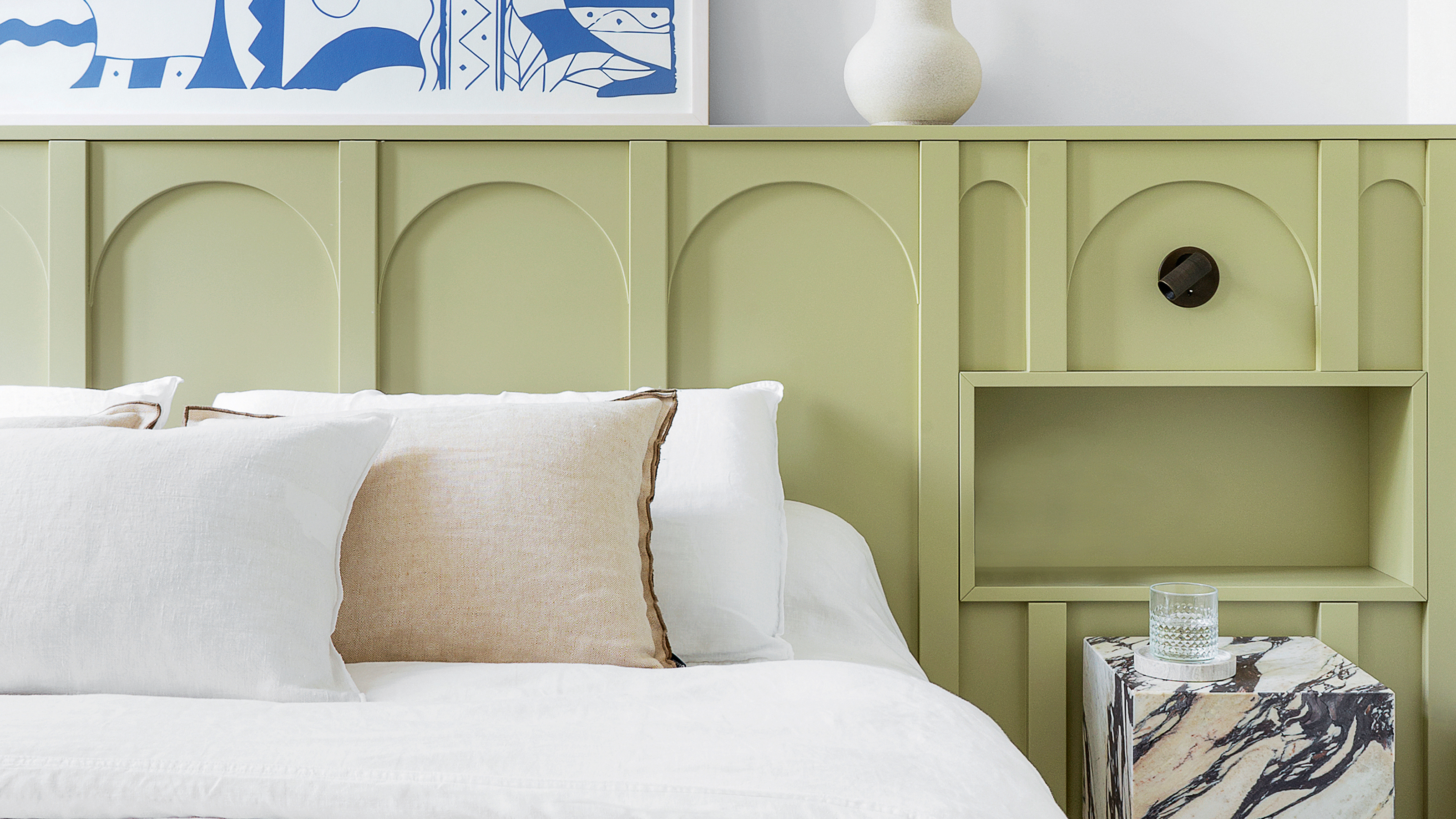 A bedroom with green wall panelling behind the bed