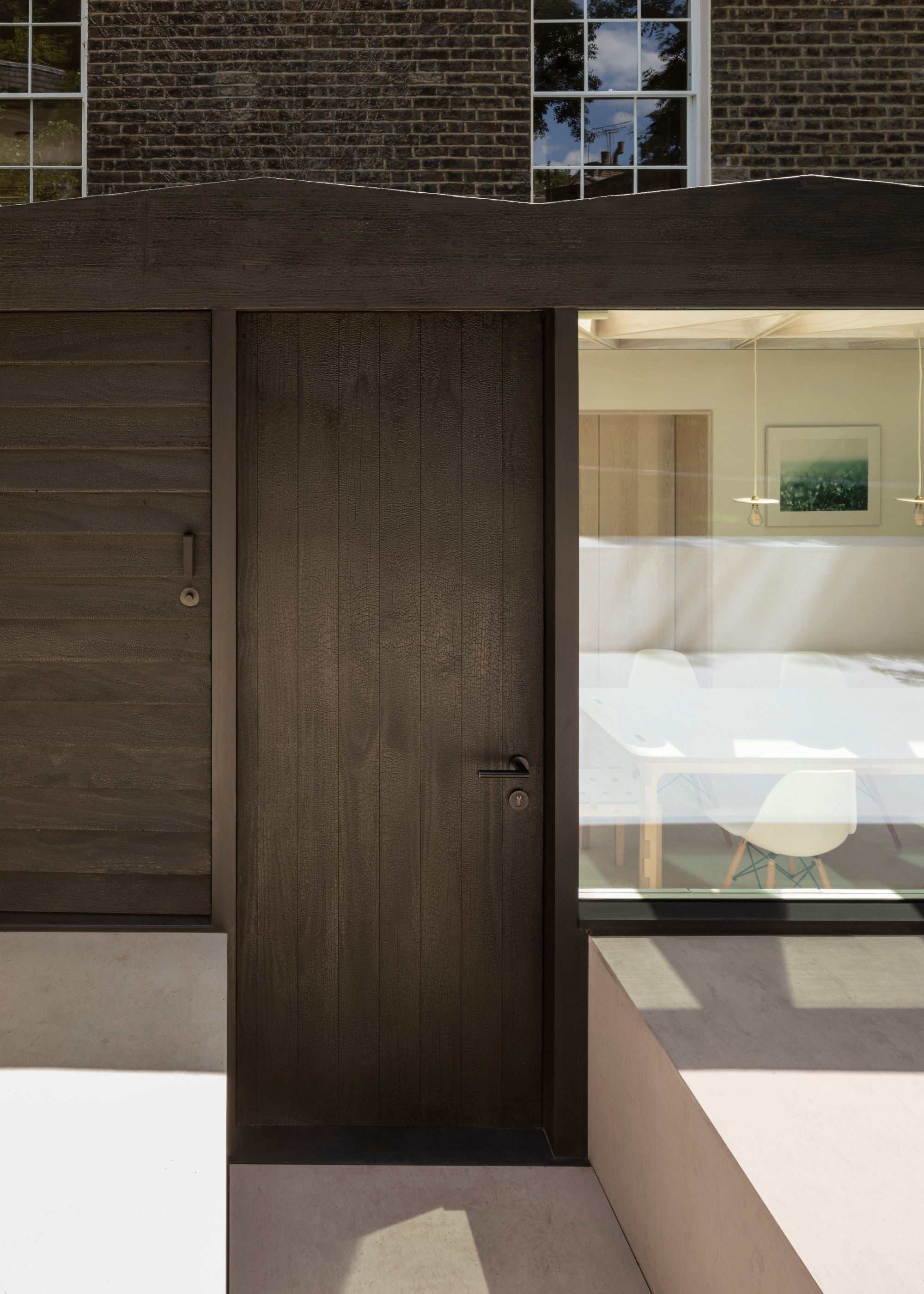 A dark wood extension of a home that uses the technique of Shou Sugi Ban.