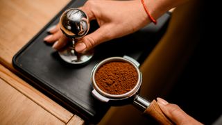 A portafilter filled with coffee grounds demonstrating how to make espresso