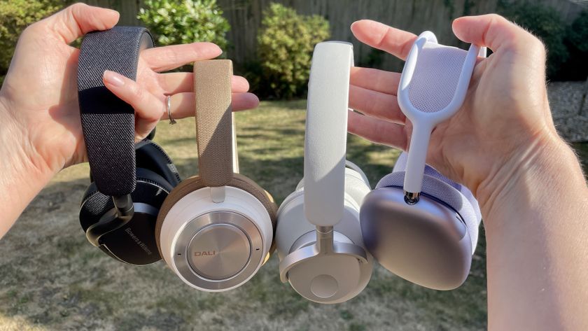 A selection of over-ear noise-cancelling headphones held in two hands, in a garden 