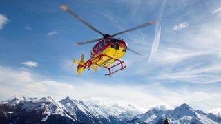 Search and rescue helicopter flying over mountain range