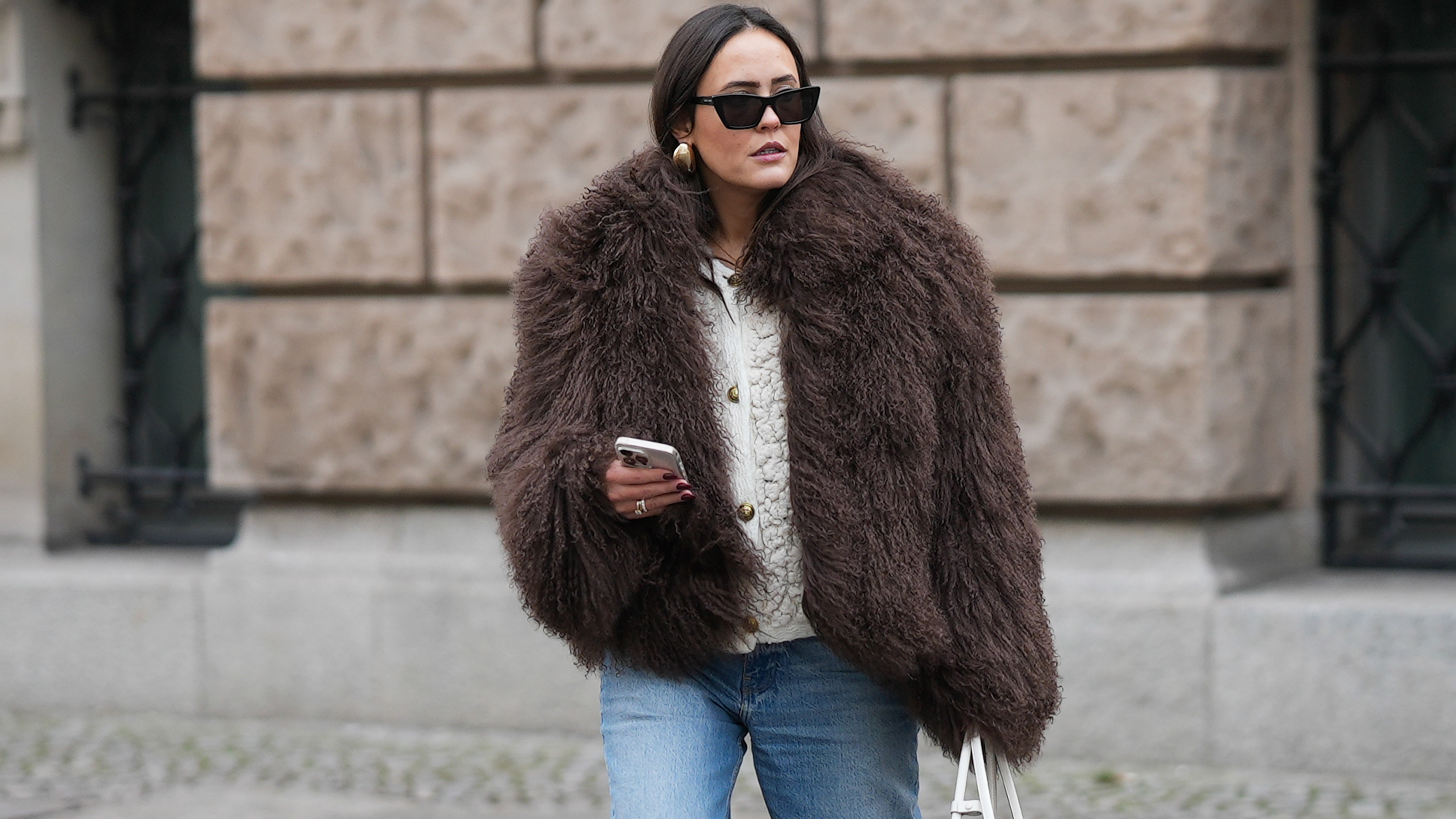 Laura Noltemeyer in Berlin, Germany, wearing a brown fur coat, a white sweater, and light-wash jeans. 