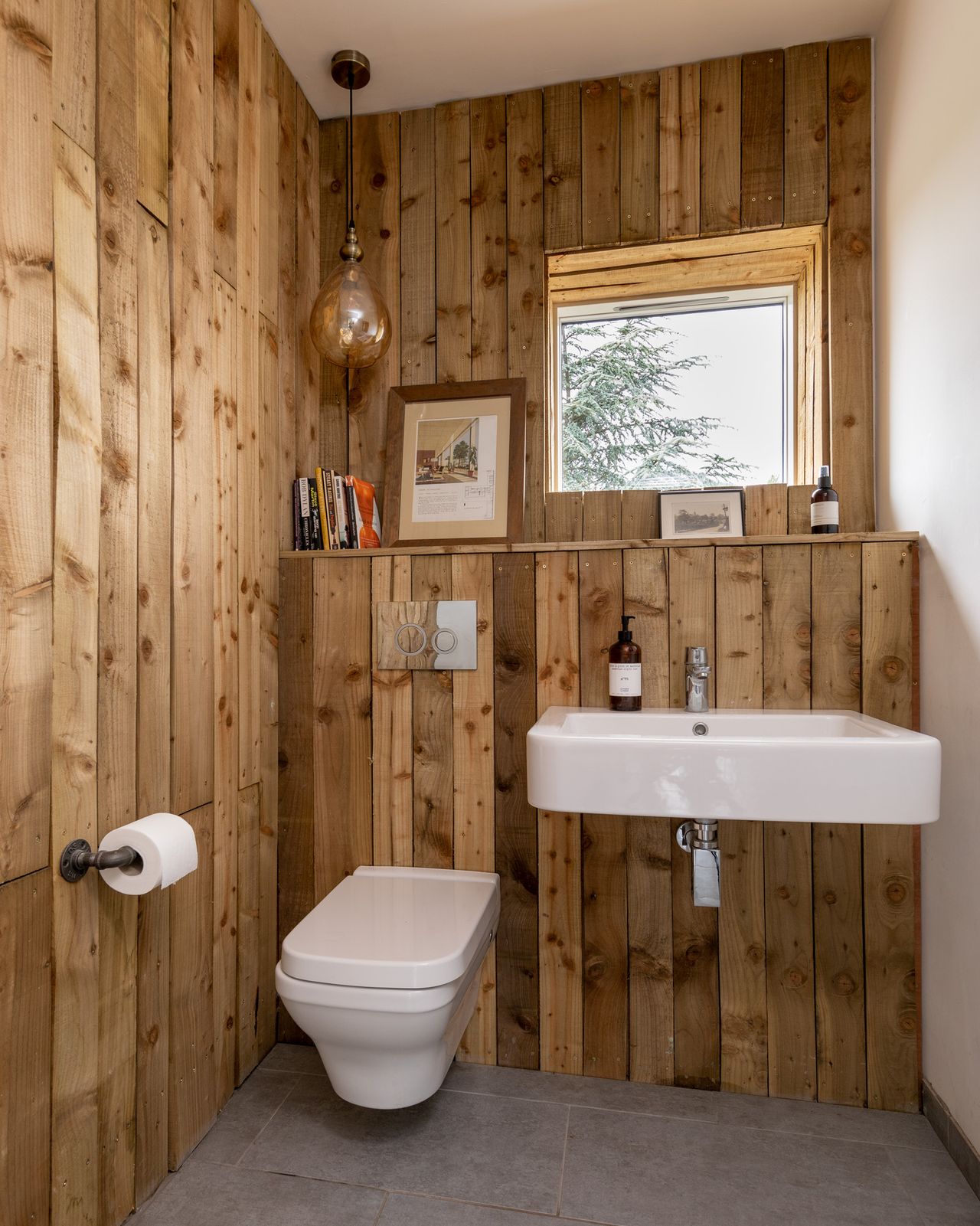 The downstairs cloakroom is finished in rough timber cladding, with pendant lighting from MyFurniture.