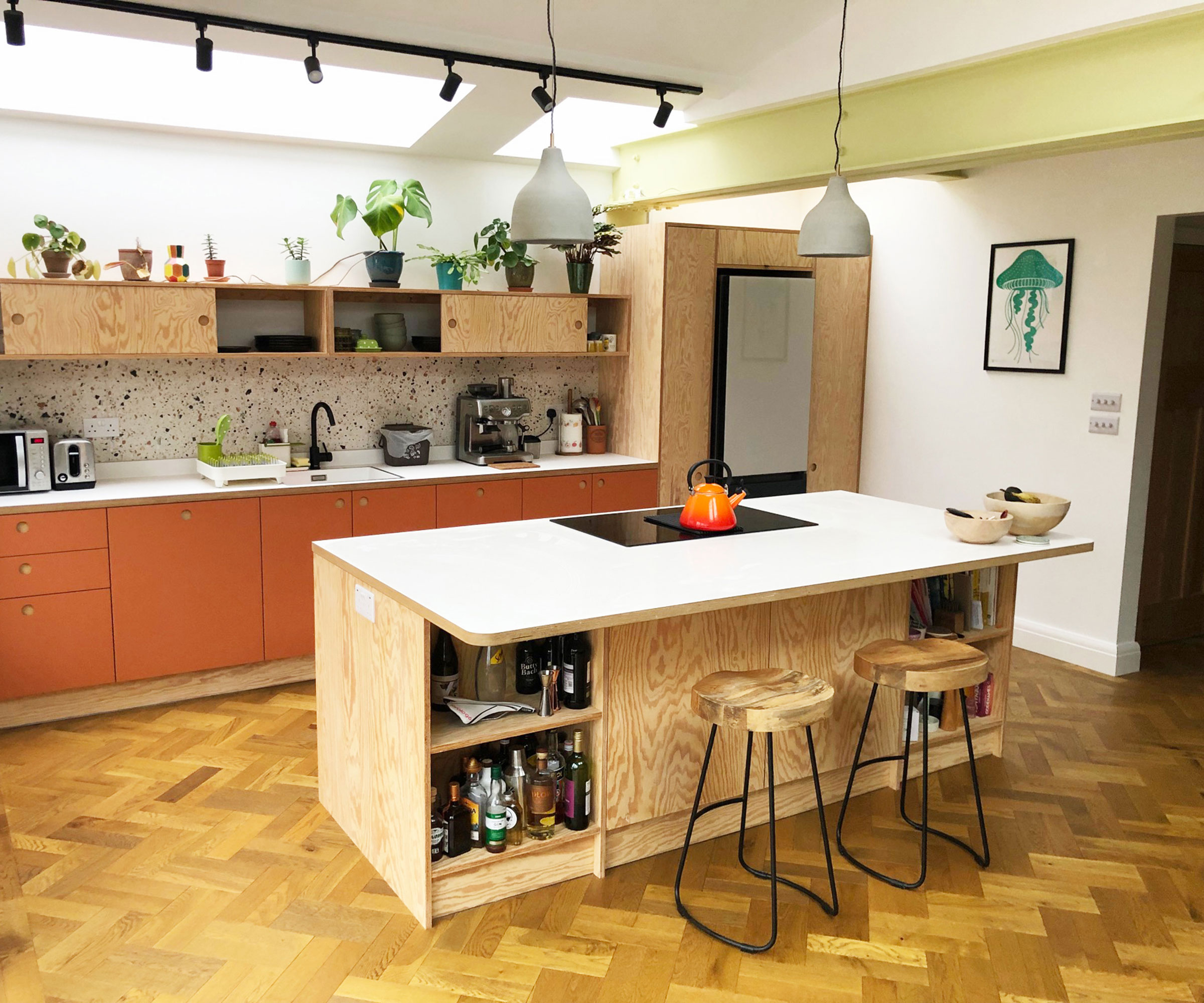orange plywood kitchen with herringbone wooden flooring