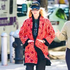 Jennifer lawrence wears a shania hat, red jacket, black pants, and black ballerina sneakers.