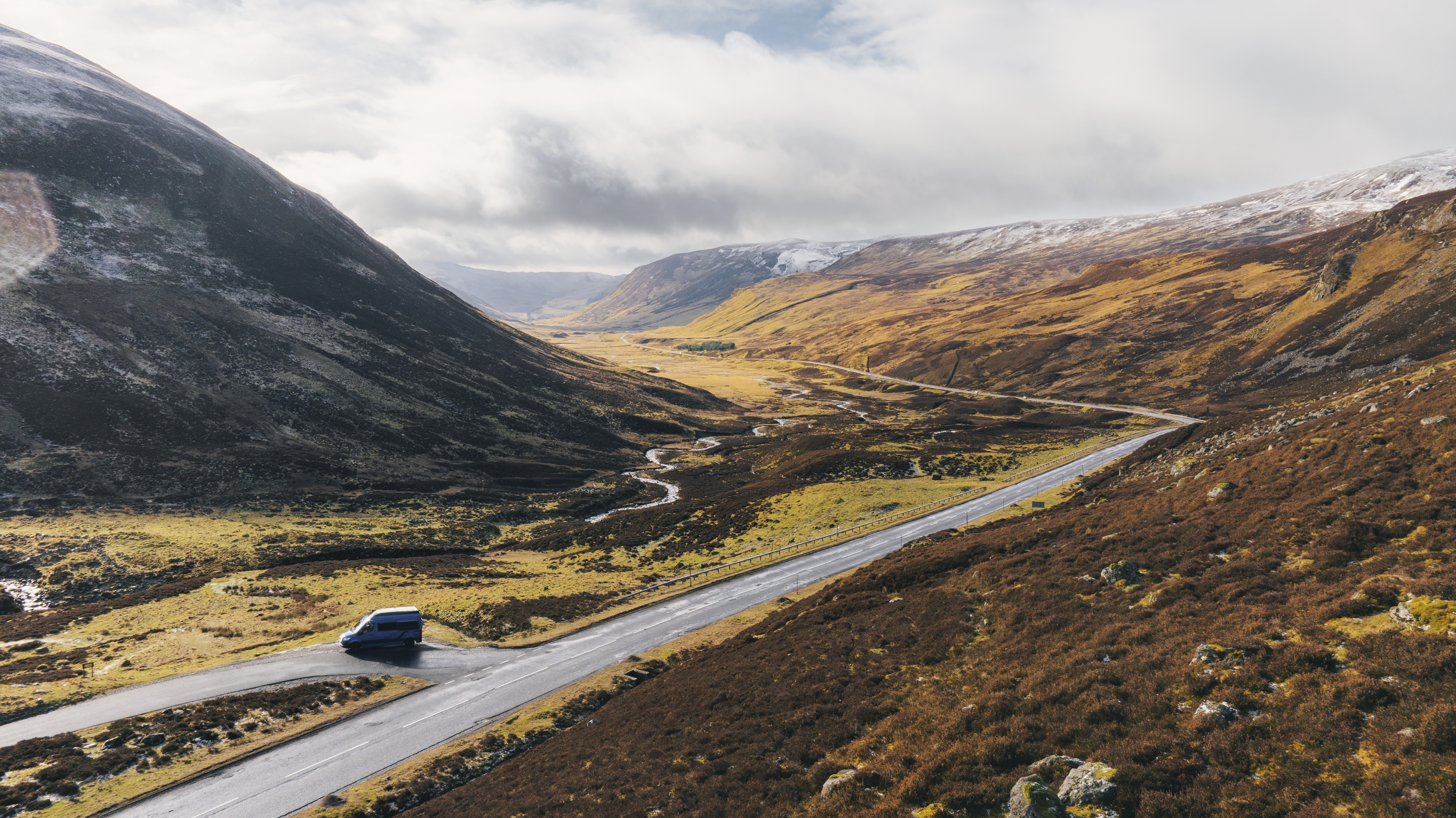 A view of a valley with a campervan parked on a road