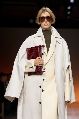 Woman on Bottega Veneta runway with white coat and burgundy bag