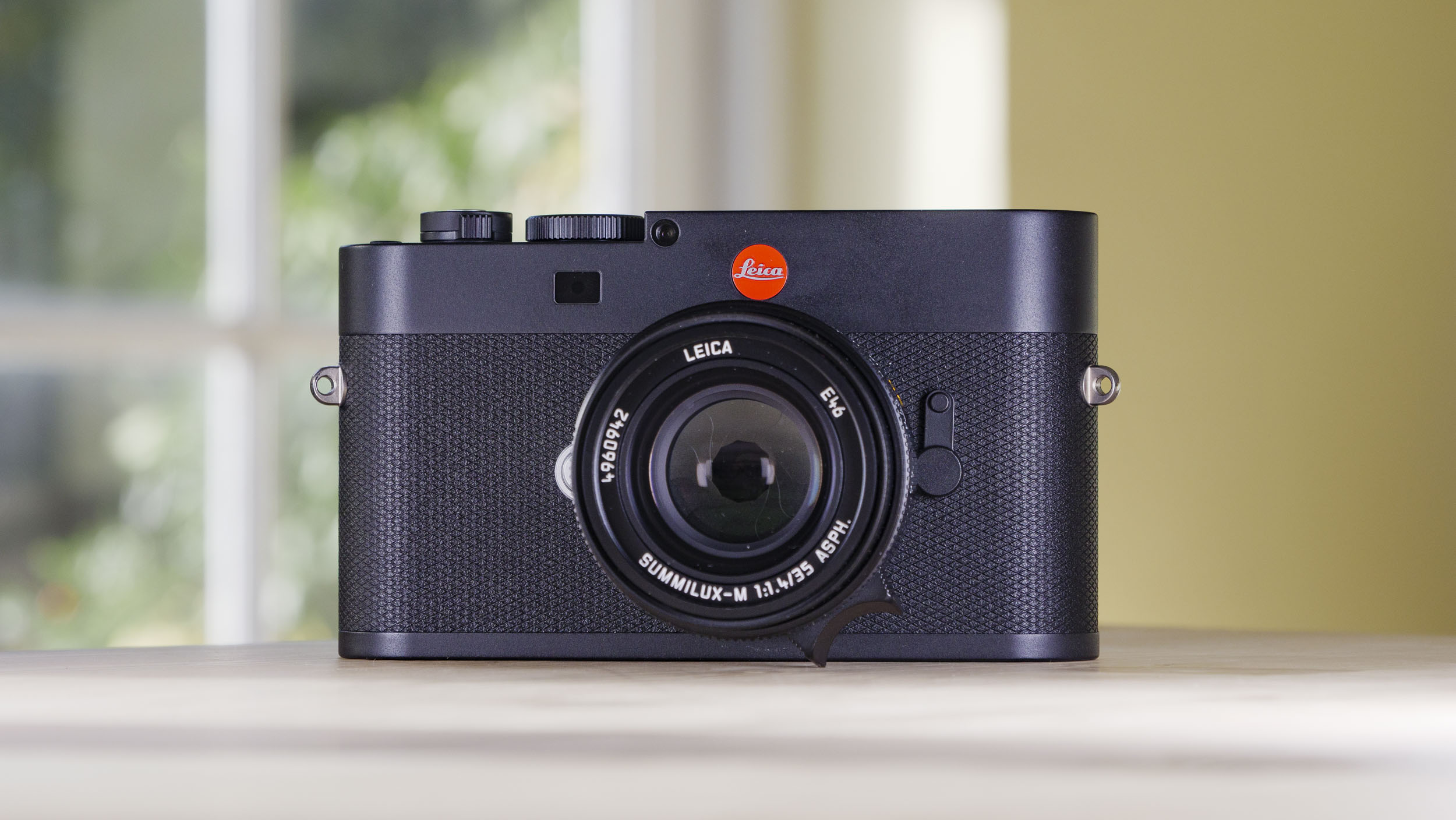Leica M EV1 camera on a wooden table with glass-panelled door backdrop