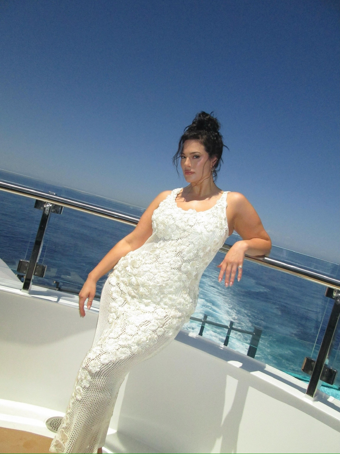 Plus size model wearing white dress on boat.