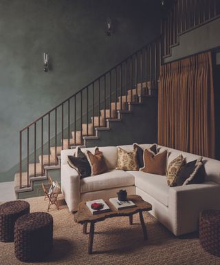 living room with cream corner sofa and dark walls and stairs in background and rush rug and coffee table