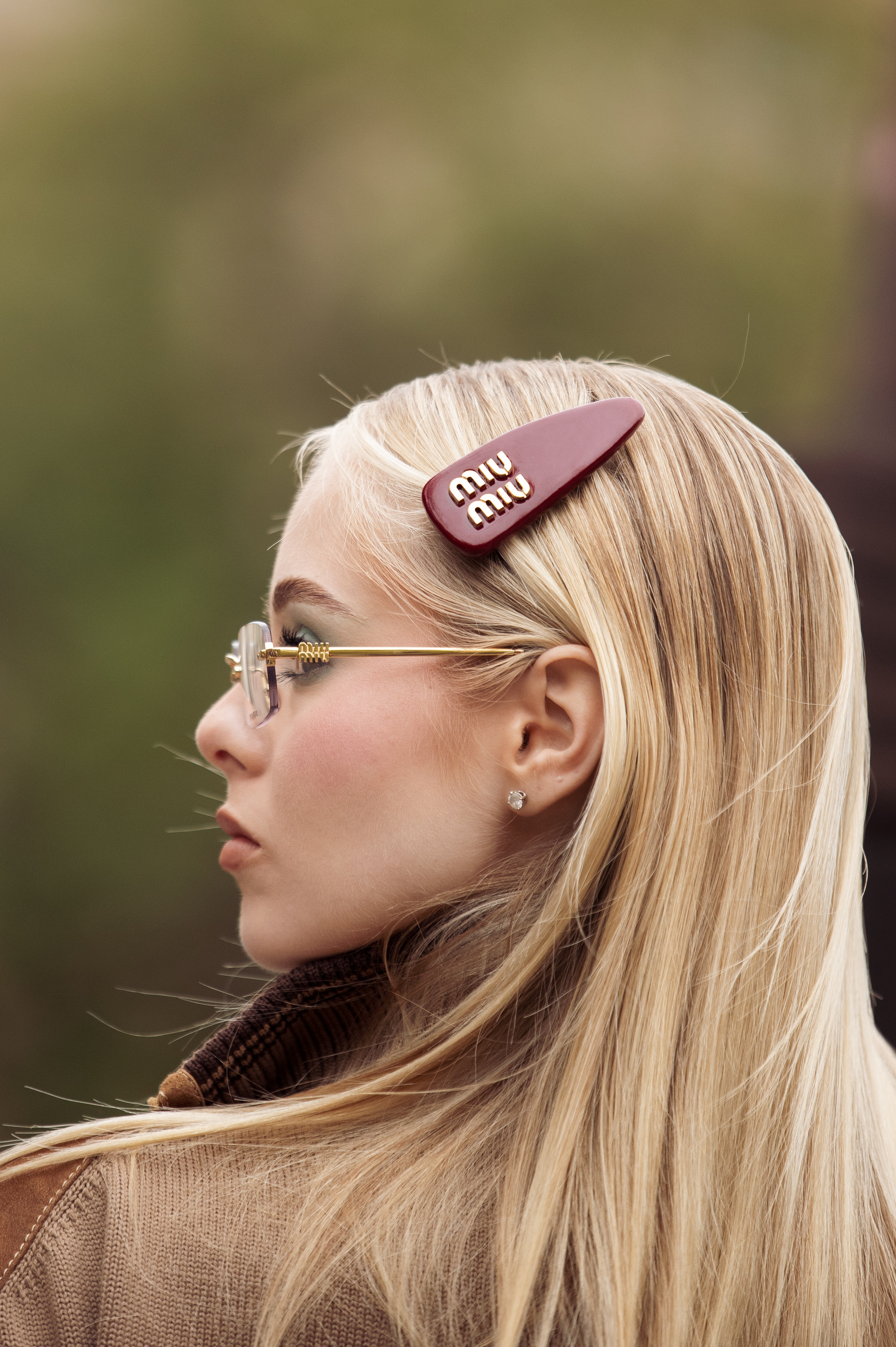 person with straight blonde hair wearing a large burgundy Miu Miu leather hair clip