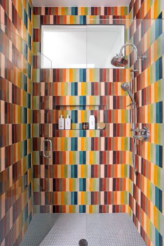 Shower enclosure with rainbow vertical subway tiles and mosaic tile floor