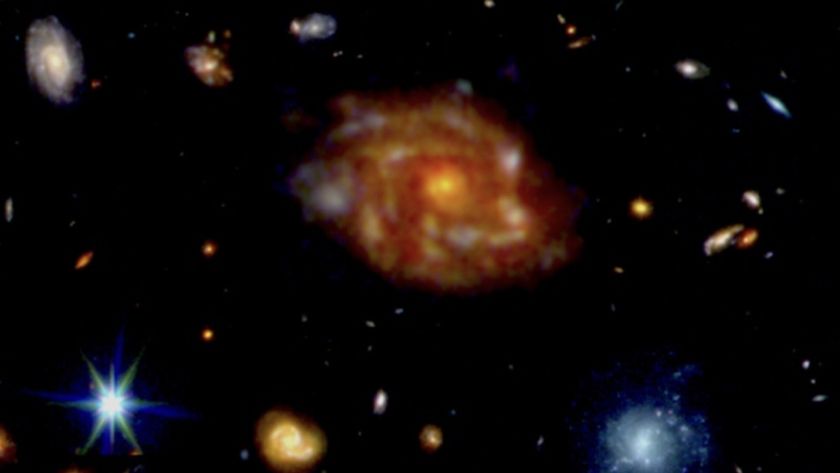 a photo of a very large orange galaxy next to other smaller galaxies