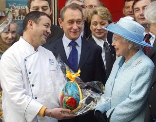Queen Elizabeth II receives a chocolate Easter egg from pastry chef Francois Duthu (L) while Paris Mayor Bertrand Delanoe watches, as the monarch visits Rue Montorgueil in Paris