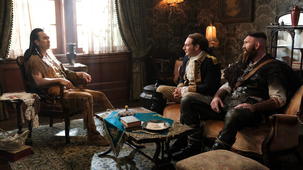 Sas sitting in an arm chair facing Isaac and Thor who are sitting on a couch.