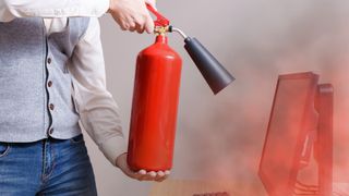 Un hombre utiliza un extintor para detener un incendio en su ordenador