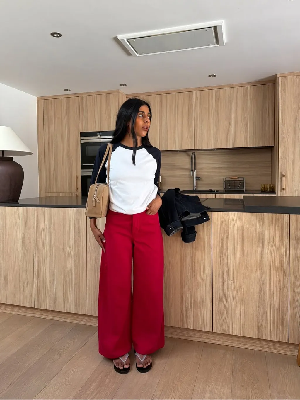 An image of @monikh wearing red jeans, one of the biggest jean trends for summer, with a raglan top and flip-flops.