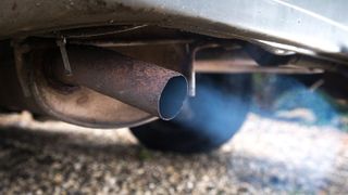close up image of a car's exhaust pipe blowing out fumes