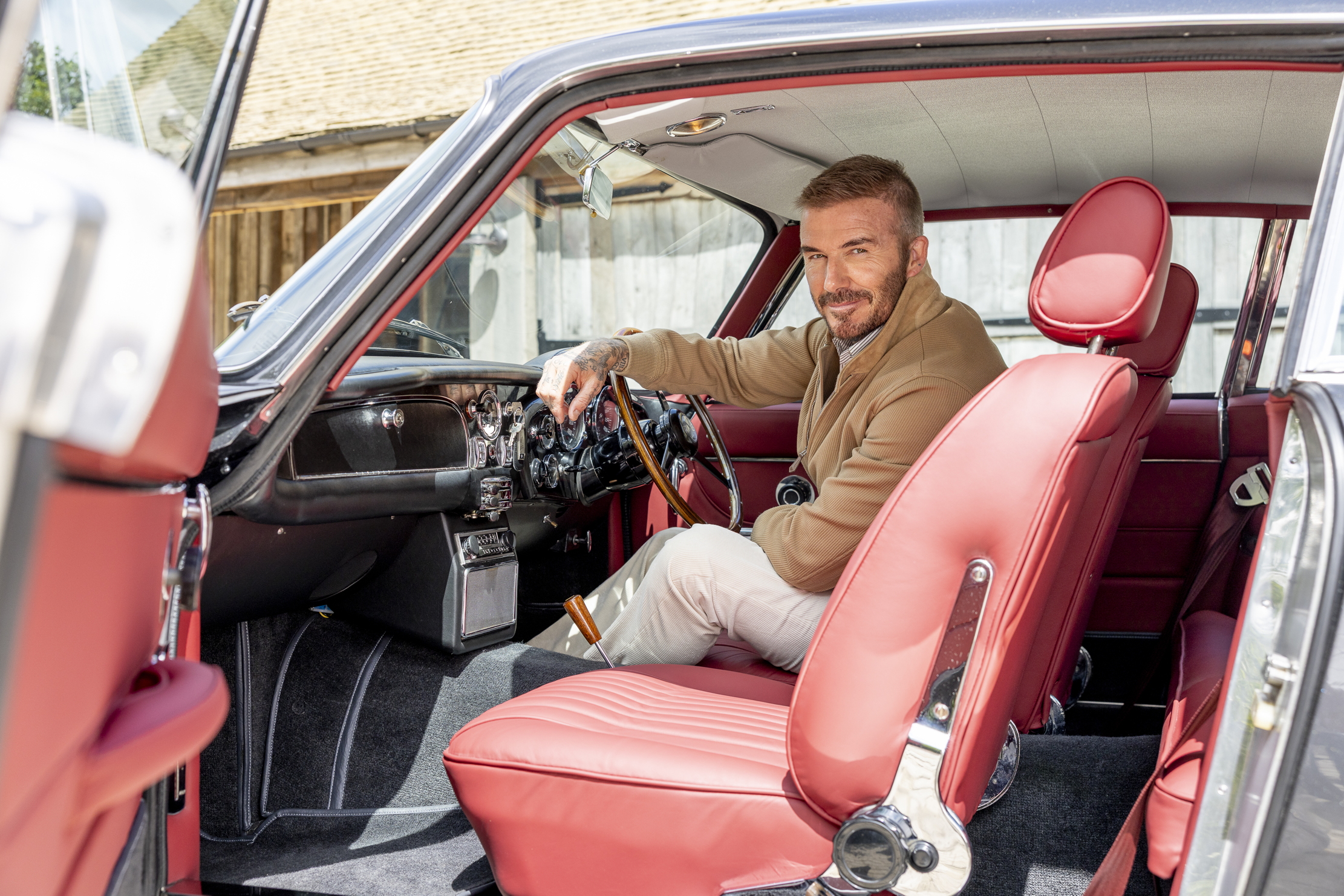 David Beckham stands beside his Aston Martin DB6