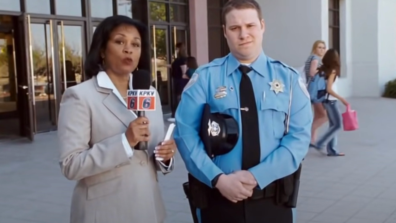 Seth Rogen is interviewed by the news in his mall cop uniform.