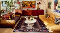 Image of a mid-century style, maximalist living room with a yellow couch on one side and a striped sofa on the other. There is a cheetah print rug in the middle and a white coffee table.