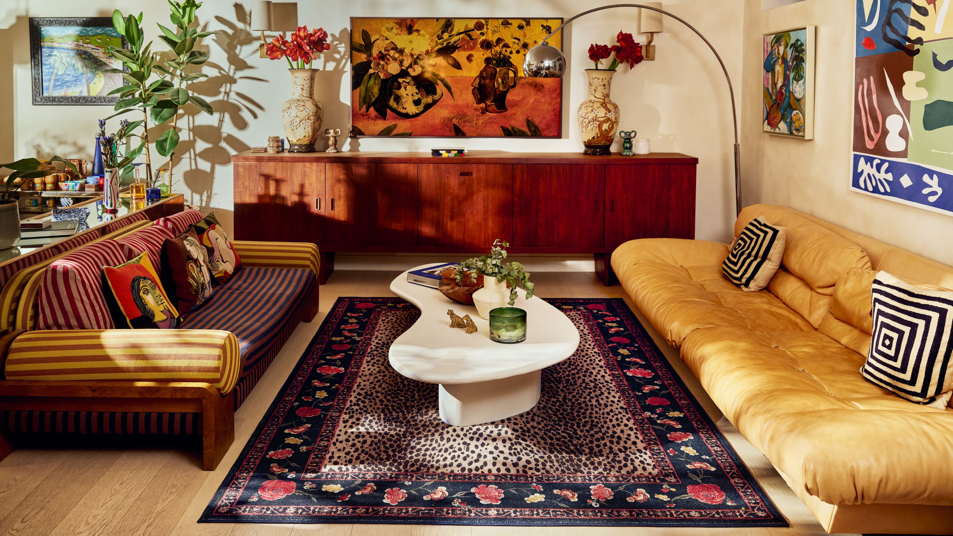 Image of a mid-century style, maximalist living room with a yellow couch on one side and a striped sofa on the other. There is a cheetah print rug in the middle and a white coffee table.