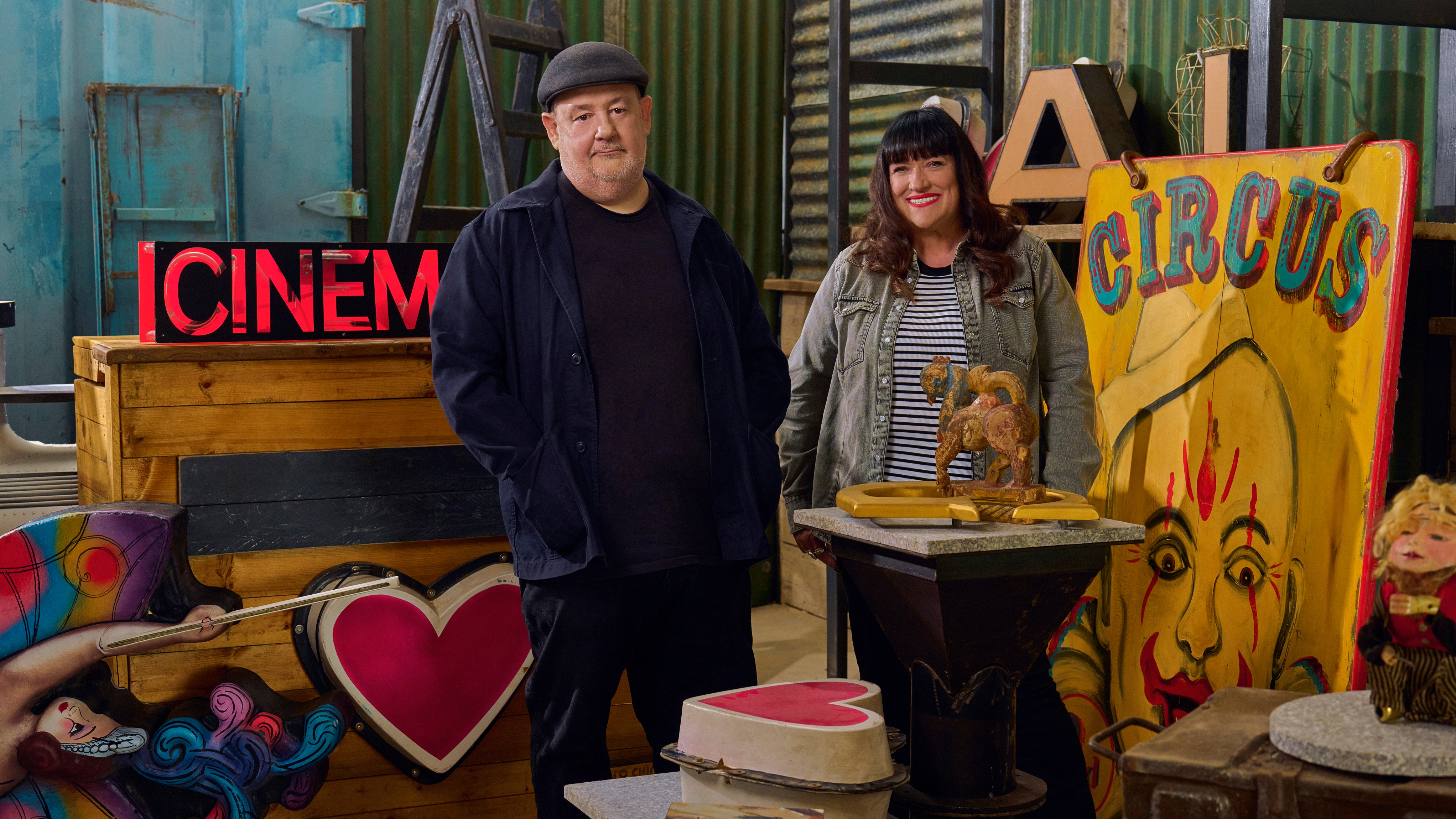 Johnny and Bev standing in the pop up antiques shop surrounded by colourful items.