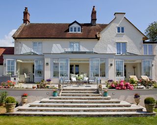 Orangery by Westbury Garden Rooms wit paved stairs leading up the the patio, and then the orangery attached to the house