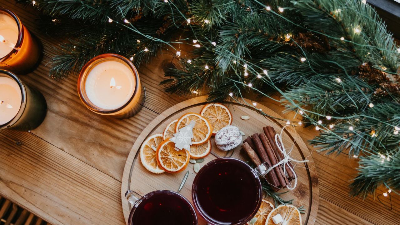 A christmas garland laid on a wooden table with a tray of dried fruit and decor beside it 