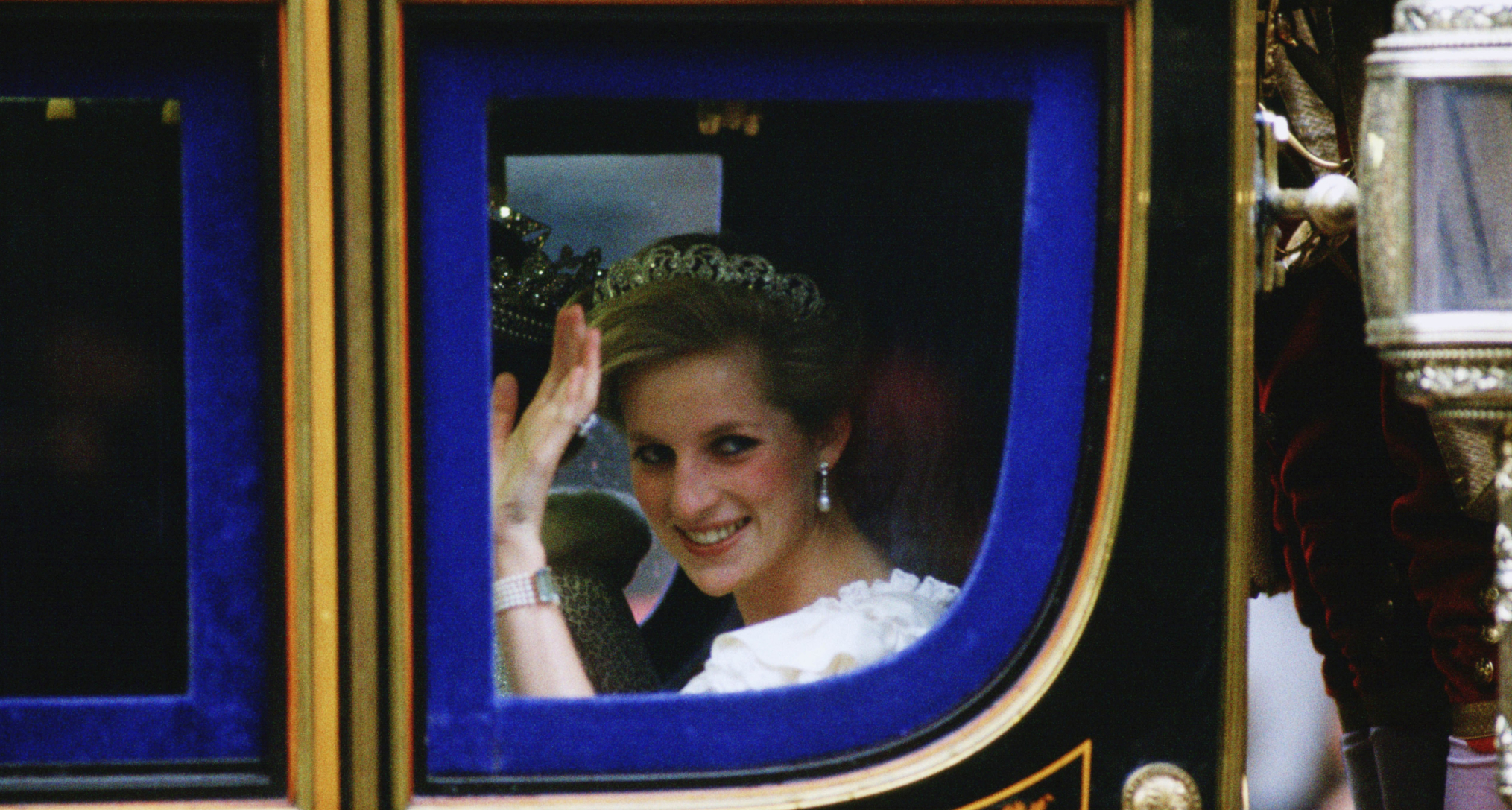 Princess Diana wearing a tiara waving from a glass carriage