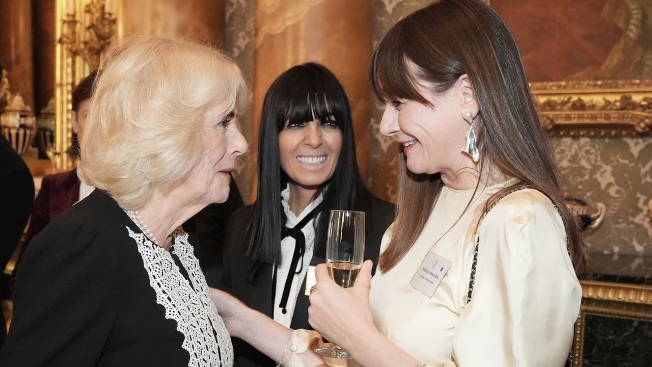 Queen Camilla wearing a black-and-white dress talking to Emily Mortimer who is holding a champagne glass 