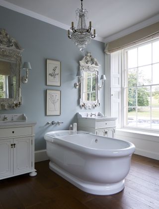 Baby blue bathroom with white sink cabinets and window frame