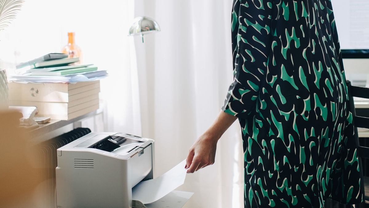 Woman using a printer in a home office.