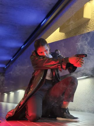 An actor holding a gun lit with a red light from the Harlowe Blade 5 & 10 LED Lighting Kit