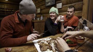 Friends eating food at a mountain hut