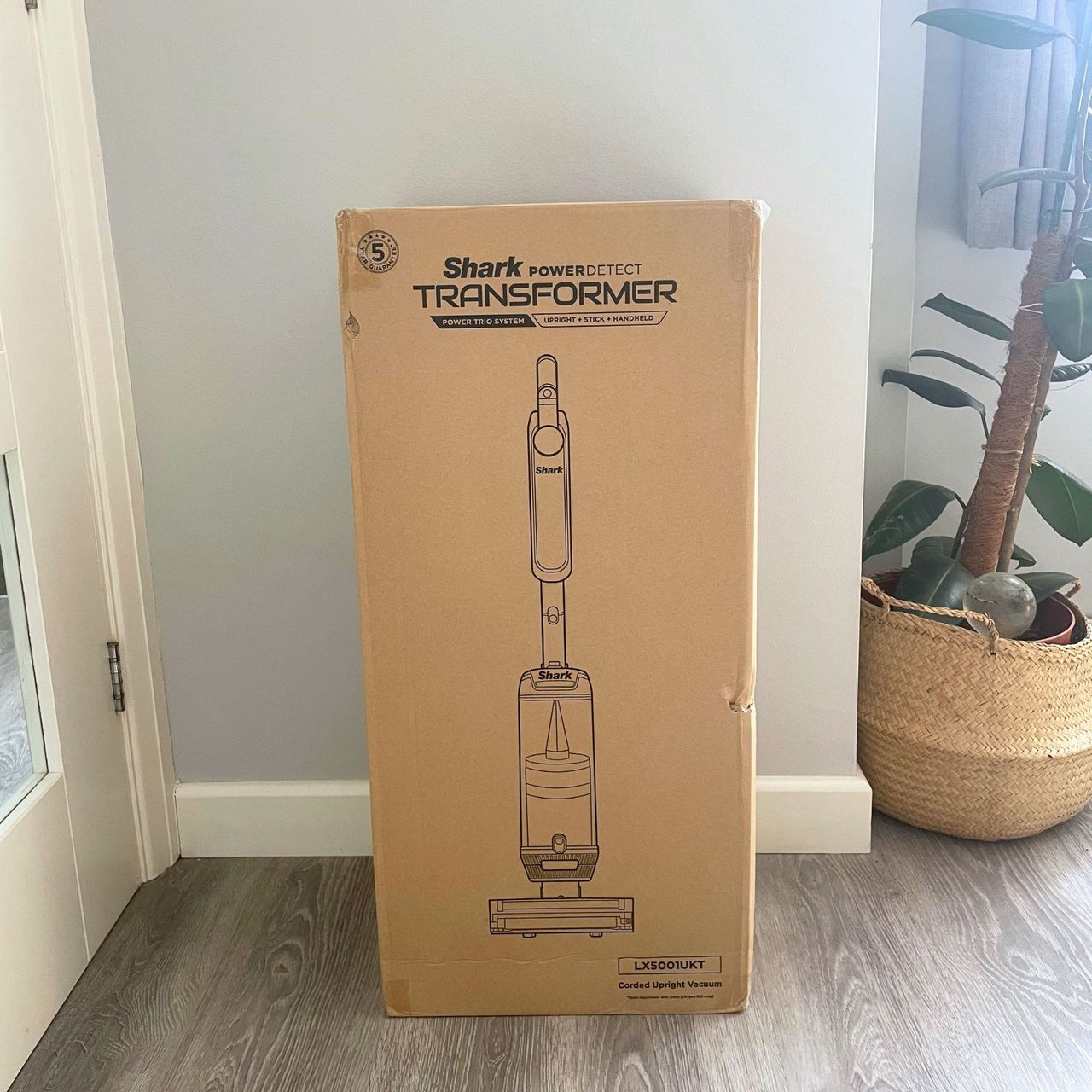 Shark PowerDetect Transformer Corded Upright Vacuum Cleaner in its box, sitting on grey flooring