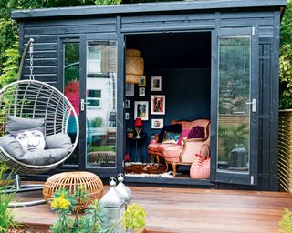 Eclectic garden room with charcoal shell and interior, styled with vintage couch, woven pendant light, glam cushions, and framed gallery wall idea.