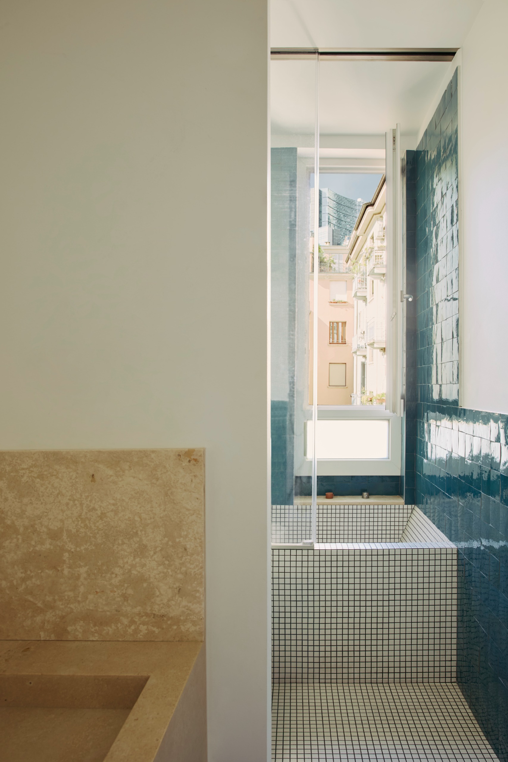 Small built-in tiled tub in an ensuite bathroom with a window that looks over milan