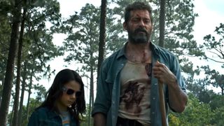 Hugh Jackman as Logan and Dafne Keen as Laura standing together in the woods during Logan.