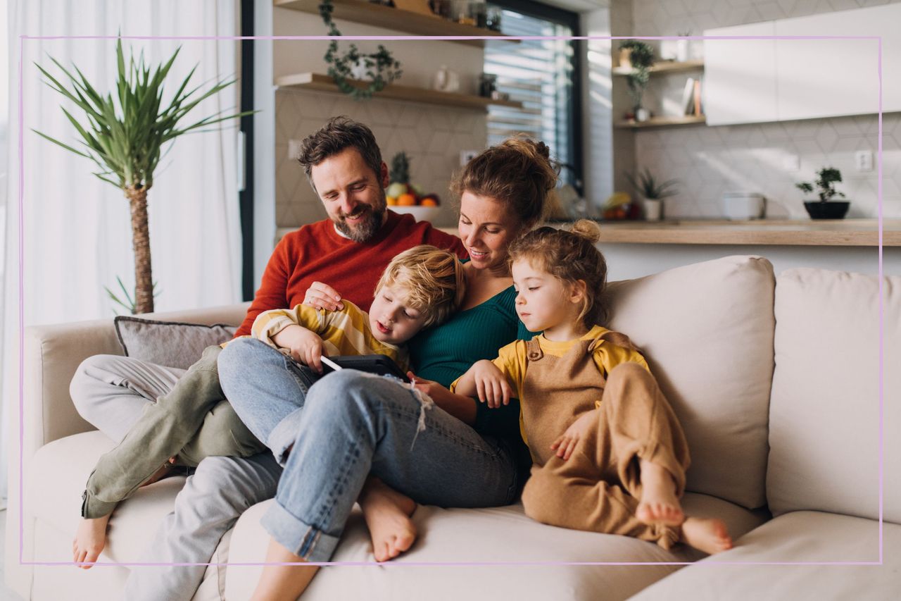 A family sat on a sofa looking at a tablet