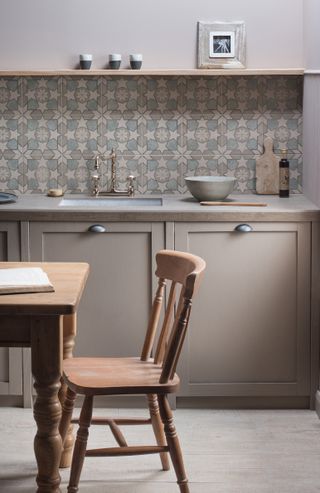 Kitchen backsplash with patterned tiles and matching beige cabinetry by Original Style