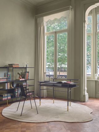 office with green walls and woodwork, herringbone floor, rug, black and metallic slimline furniture