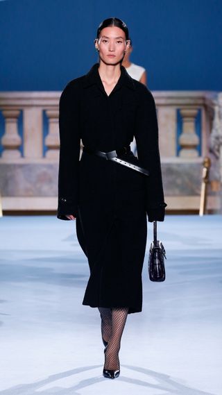 Woman on runway wearing black Tory Burch coat