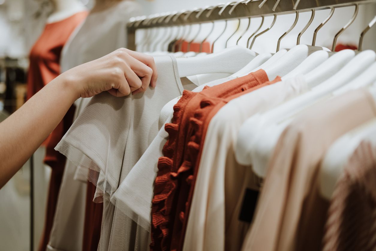 A woman reaches for clothes on a rack.