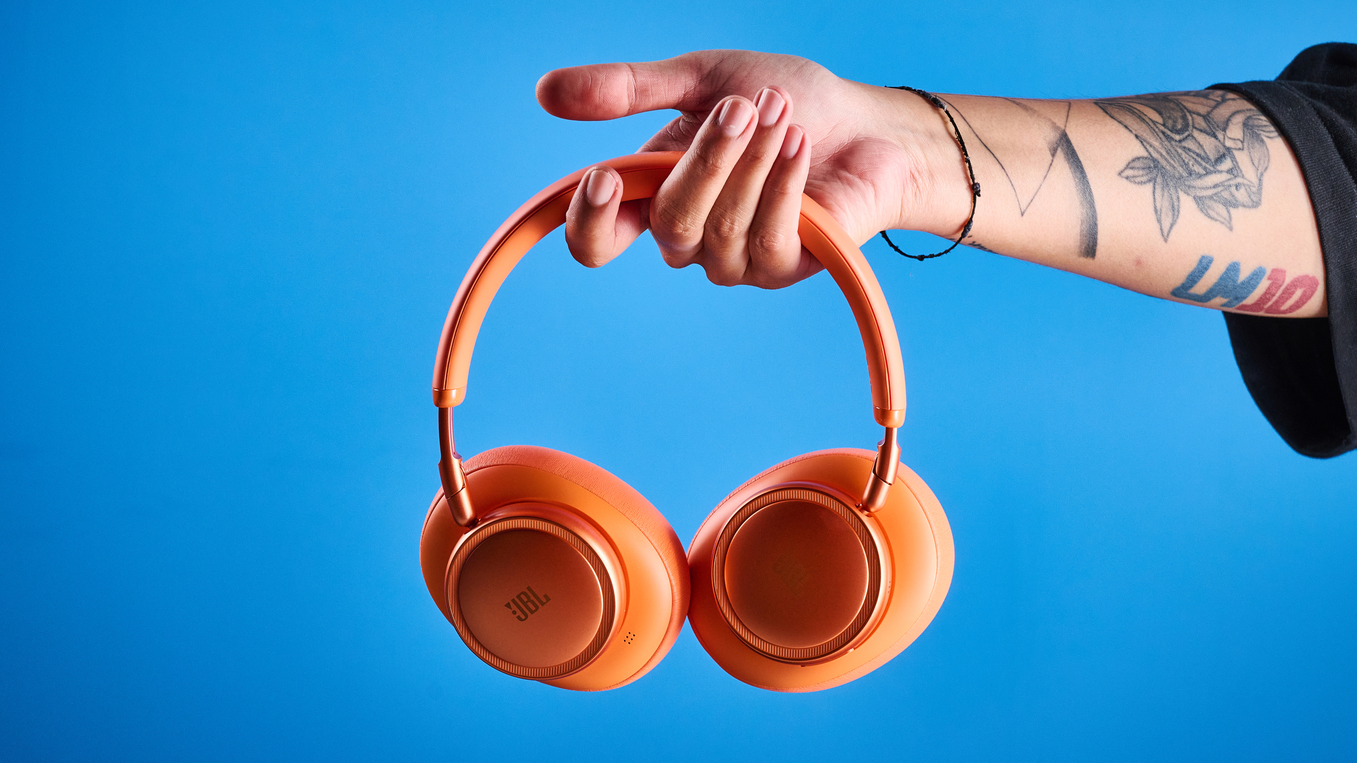 the jbl live 780NC in orange photographed against the blue tom's guide background