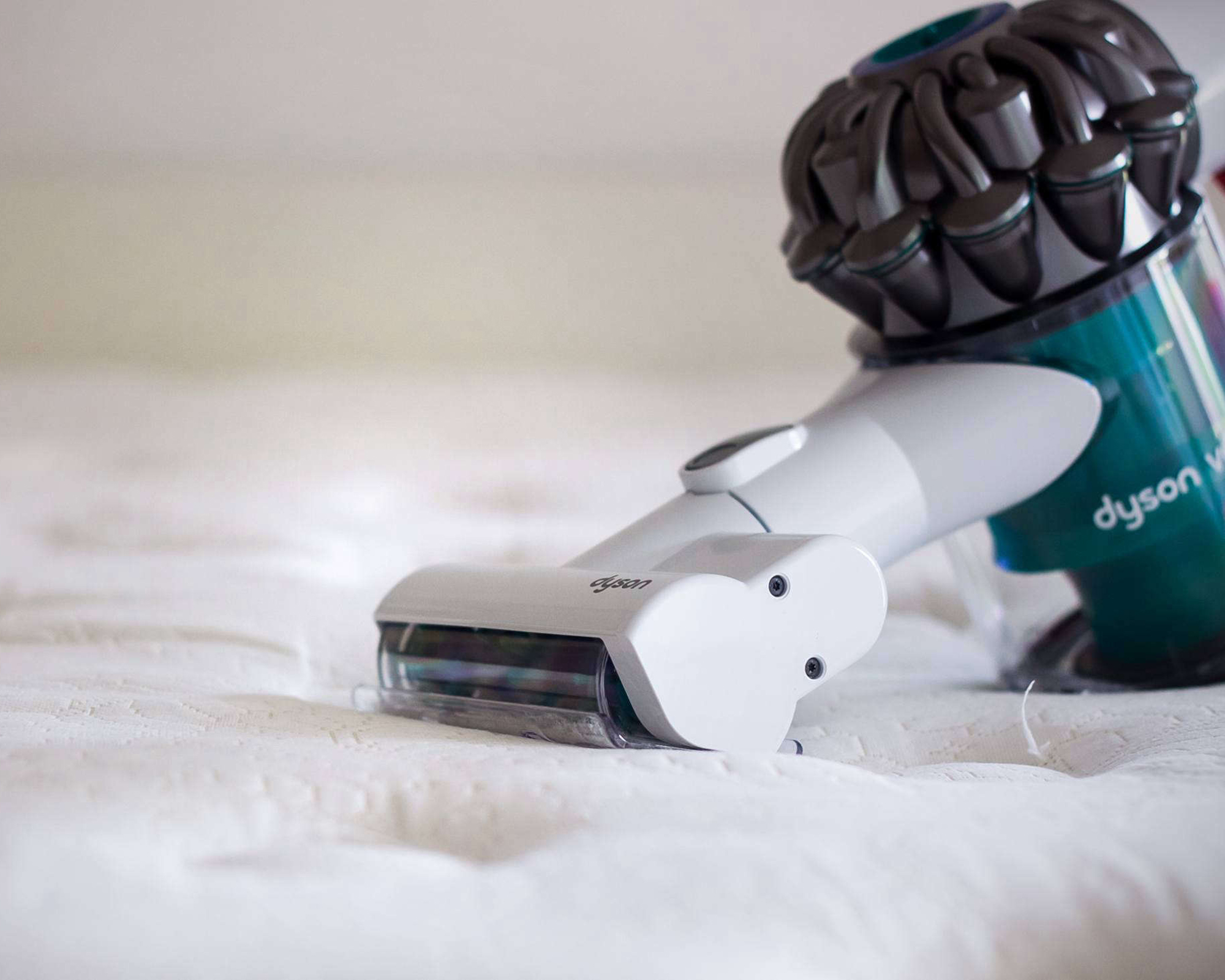 A mattress being cleaned with a Dyson handheld vacuum cleaner