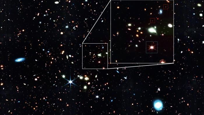 An image of a starry section of space; some little red sparkles are pointed out.