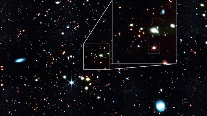 An image of a starry section of space; some little red sparkles are pointed out.