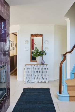 Blue accent stairs in an entryway with traditional elements and a blue rug