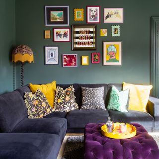 Green living room with gallery wall above blue velvet sofa